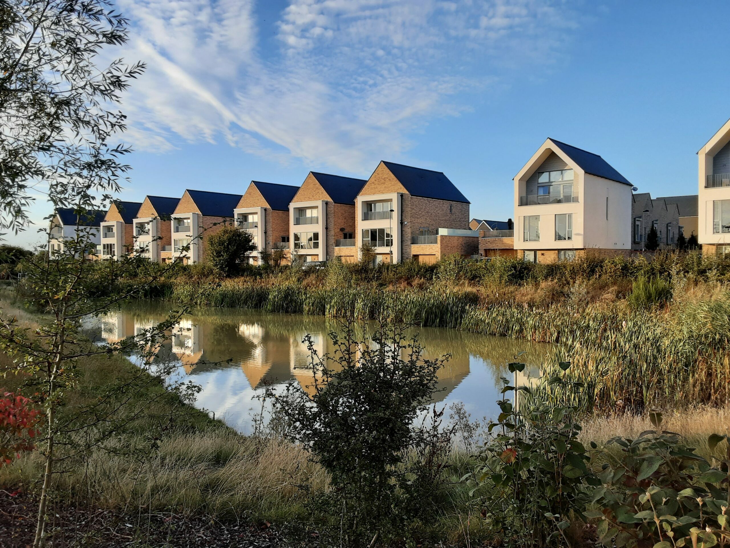 A photo of new, modern-looking homes, looking out over a river. Blue skies in the background