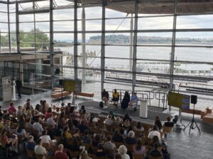 Image of the audience and the 4 panel speakers in the Senedd