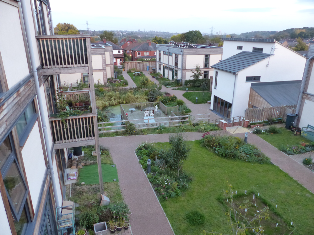 Bird's eye view of the outdoor space at LILAC, a co-housing community in Leeds. Green space and paths are between the buildings.
