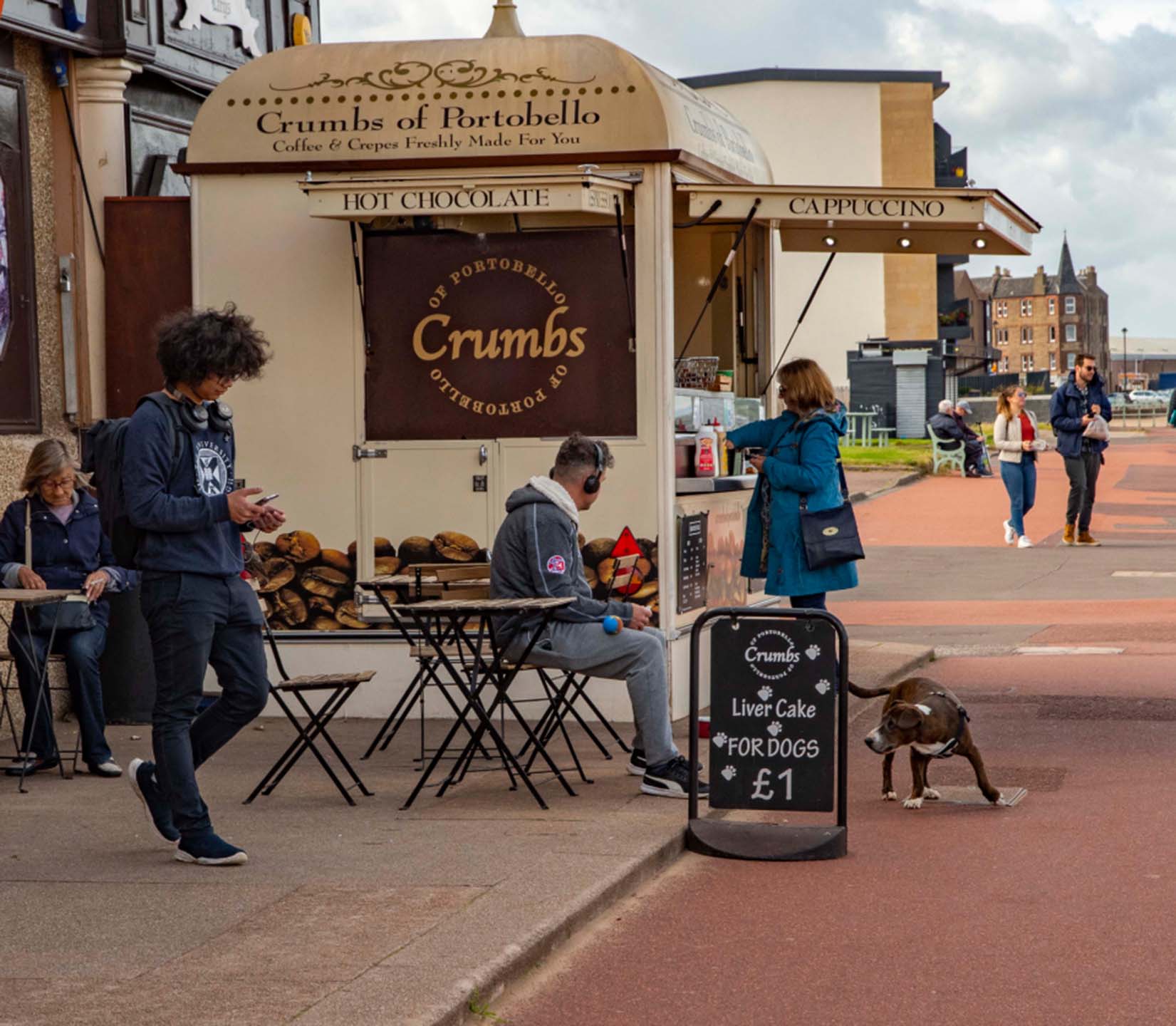 an image of a coffee stand whilst people are sat down or walking past the stand